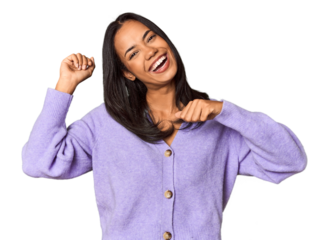 Young Filipina with long black hair in studio celebrating a special day, jumps and raise arms with energy.