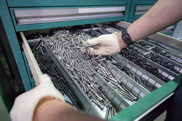 A worker selects and shows bolts lying in a hardware box.