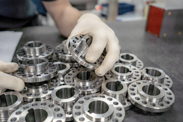 A worker inspects and sorts round parts with holes for assembling them into components and...