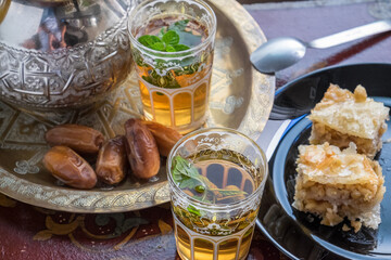 Vasos de té marroquí con dátiles y dulces de pistacho con miel