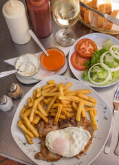Carne, huevo frito, patatas y ensalada, en un restaurante