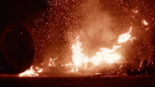 Flames and smoke from tires on the fire at night. People on protest riot
