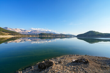 Reflection of trees and green leaves in the lake water. Liquidambar orientalis protected area in Burdur Turkey. Karacaoren ( barrage ) dam lake. Panorama.