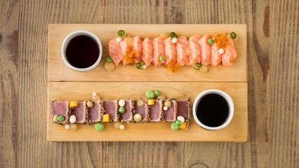 Salmon sashimi and tuna with soy sauce dip, wasabi on planks on wooden background