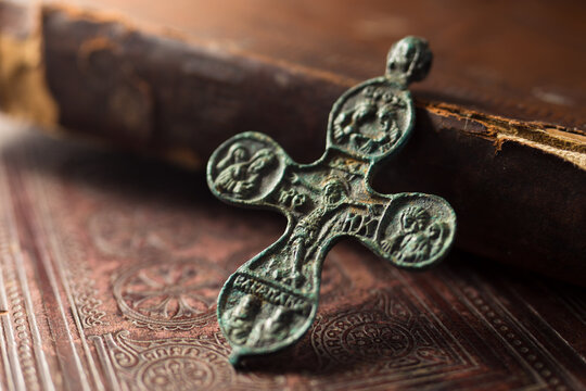 Antique bronze cross with patina on ancient books
