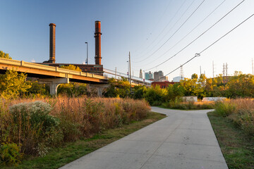 Lovely urban greenway walking trail path through city at sunset with city buildings in background © Kathryn