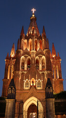 Naklejka premium The fascinating front facade of the church/cathedral Parroquia de San Miguel Arcangel in San Miguel de Allende at night, Mexico
