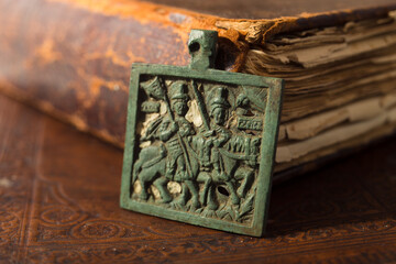 Ancient bronze church icon on leather cover of the bible. Old icon with ancient books.