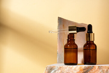 Fototapeta na wymiar Cosmetic serum in an amber glass bottle with dropper lid with granite stone for composition
