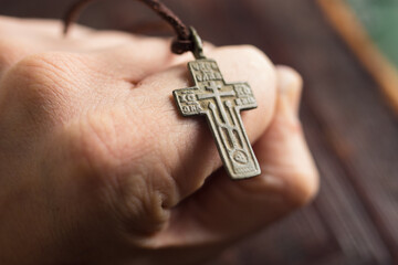 A man hold ancient cross. Cross, church books, bible - symbols of Christianity.