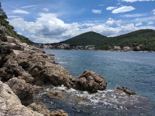 Fototapeta na wymiar a rocky beach with a few water on the rocks, on a bright blue sky