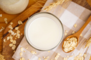 Glass and jug of fresh milk on wooden table against color background. Top view.