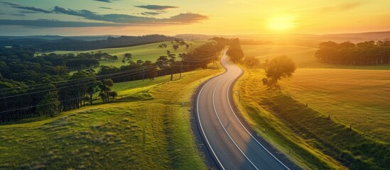 Sunset view of Australian countryside road passing agricultural land captured from above.