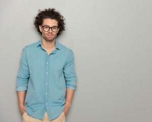 curly hair man with glasses in denim shirt holding hands in pockets