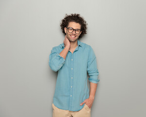 happy handsome man with glasses holding one hand on neck and posing
