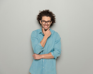 happy casual man with curly hair crossing arms and touching chin