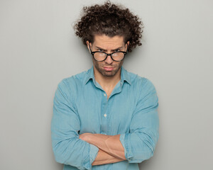 Fototapeta na wymiar sexy guy with curly hair and glasses crossing arms and making a cute upset face