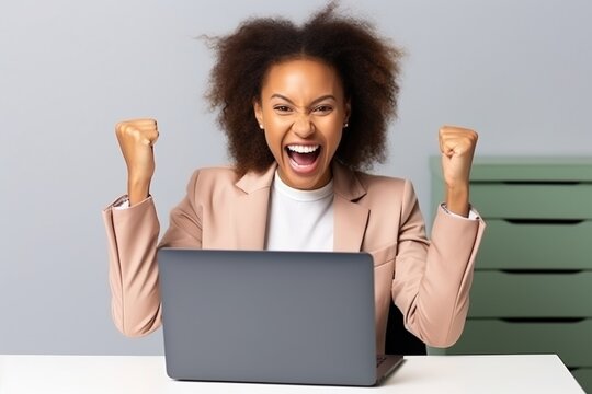 African American woman celebrating her success in front of laptop