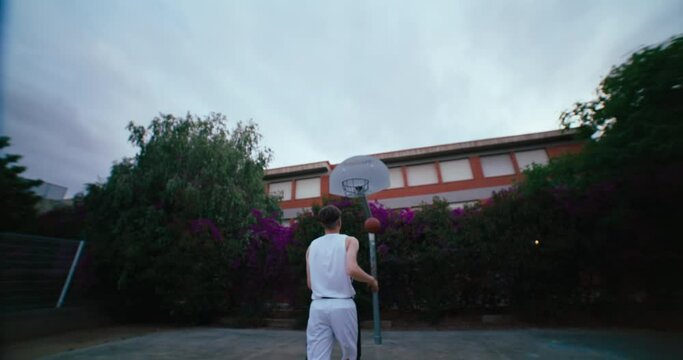 Low angle wide shot of basketball player attempt to score ball in the hoop and miss the shot. Sport practicing and training on outdoor court. Street basketball