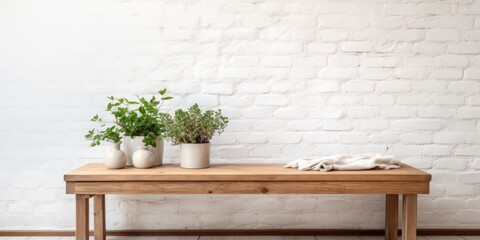 Wooden table near bench with cloth, potted plant, and white brick wall.