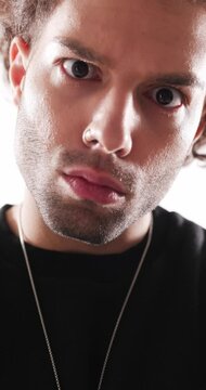 close up video of serious casual man in black hoodie looking forward in an insistent way while being curious on grey background