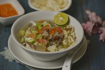 Mie kocok Bandung, Indonesian beef noodle soup served with emping crackers and chili sauce. 