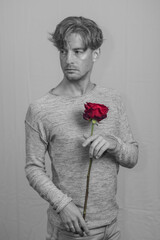 handsome attractive model male boyfriend with romantic gesture  single red rose flower on valentine's day. passionate secretive expression captures feeling for significant other on special occasion 
