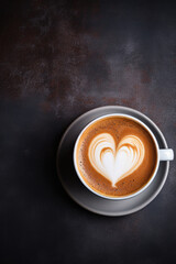 Cup of cappuccino with heart shape on dark background.