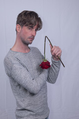 handsome but disappointed  angry male boyfriend with violently snapped red rose flower on valentine's day. jilted broken heart from lovers betrayal, raging frustration emotion on romantic day 