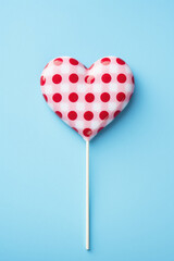 Heart shaped lollipop on blue background, valentines day concept.