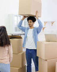 African American couple, man and woman, collect clothes and personal belongings in cardboard boxes for moving. happy young people relocating to new home. purchase of residence, mortgage or rental. 