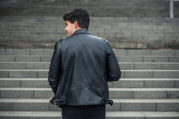 young man from behind in leather jacket climbing stairs