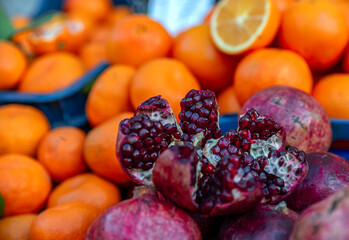 Opened pomegranate standing in front of oranges
