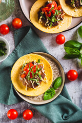 Smash Burger Tacos with beef patty, tomatoes and basil on a plate top and vertical view