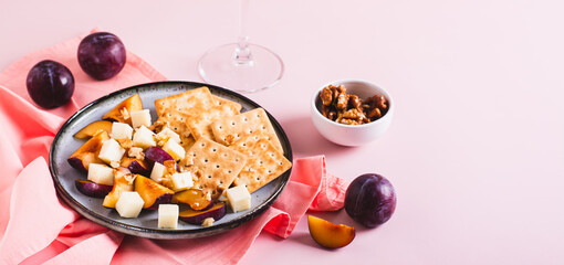 Dinner for girls, cheese, biscuits, plums on a plate and a glass of wine on the table web banner