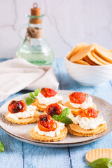 Bruschetta on crispbread with ricotta and baked tomatoes on a plate on the table vertical view