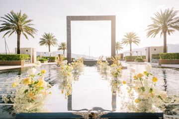 Bouquets of flowers stand in rows in a long pool with a square arch in the center