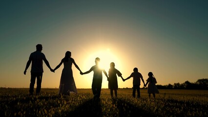 Parents, happy children go to sun. People walk in nature. Big family holding hands walk in park at sunset. Dad mom, son, daughter walk, walk together outdoors. Concept of happy family childhood dream