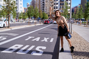 full length photo of beautiful woman beckoning the bus in the busy city. young office lady calling taxi cab standing in street
