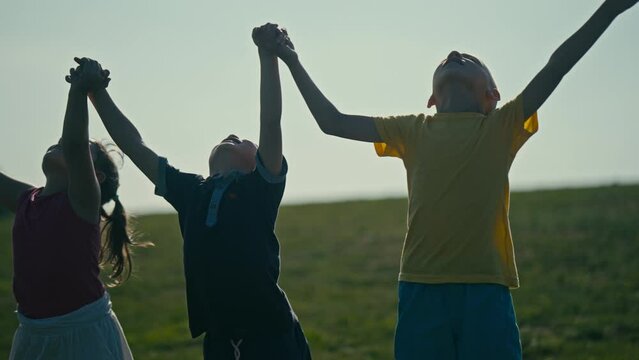 Children Standing in Unity Holding Hands Together and Looking Up