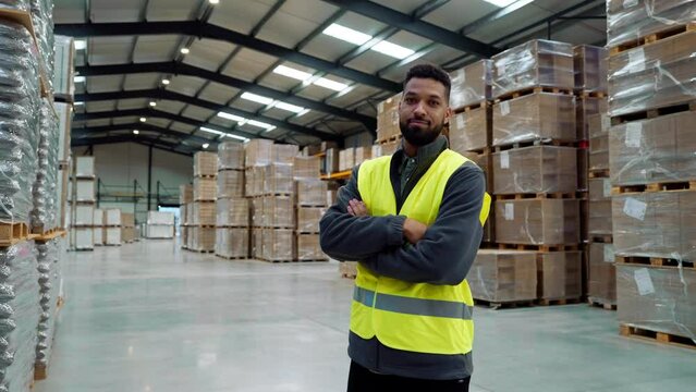 Male warehouse worker standing in warehouse. Warehouse manager checking delivery, stock in warehouse, inspecting products for shipment.