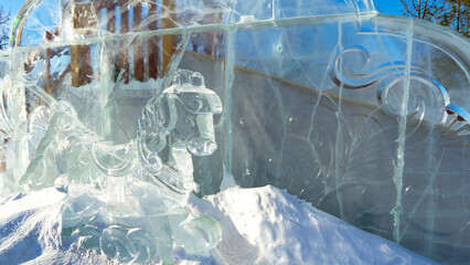 Ice sculpture of toy horse on background of snow slide in ice town. New Year and Christmas. Children's winter entertainment. Decoration of ice town