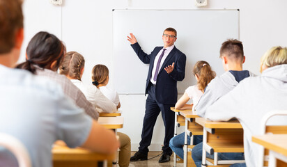 Male speaker giving lesson for teenage students in classroom