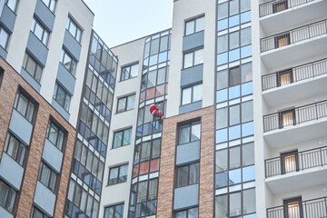 santa descends through the window of a multi-storey apartment building in order to give a gift to a child.