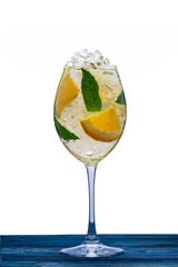 Alcoholic cocktail with fruit and ice in a glass on a long stem, strong plan