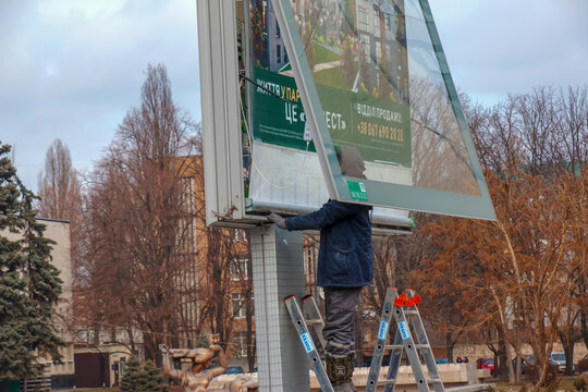 Dnipro, Ukraine - 02.09.2022: Installation of outdoor advertising in the city. Specialists climb the stairs to the billboard. Work at height.