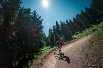 Downhill mountain biking on a shaped bike park trail in Austria, sunny blue sky day, bike leaning in the curve. - 704671708