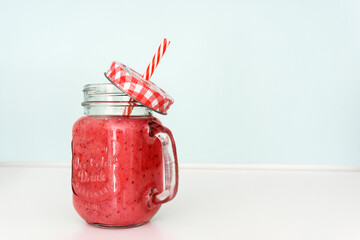 Colourful red smoothie in a jar with a straw