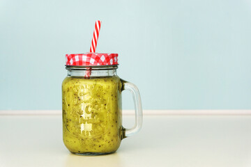 Colourful green smoothie in a jar with a straw