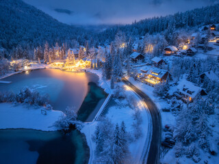 Aerial view of fairy alpine village in snow, road, forest, Jasna lake, houses, street lights at...